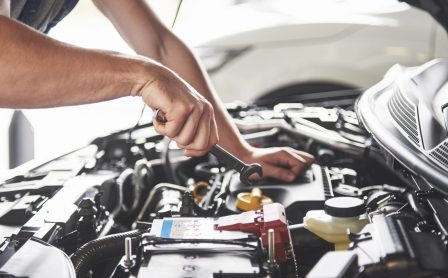 muscular-car-service-worker-repairing-vehicle